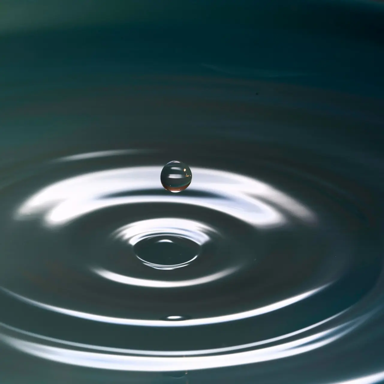 A drop of water above a rippling water.